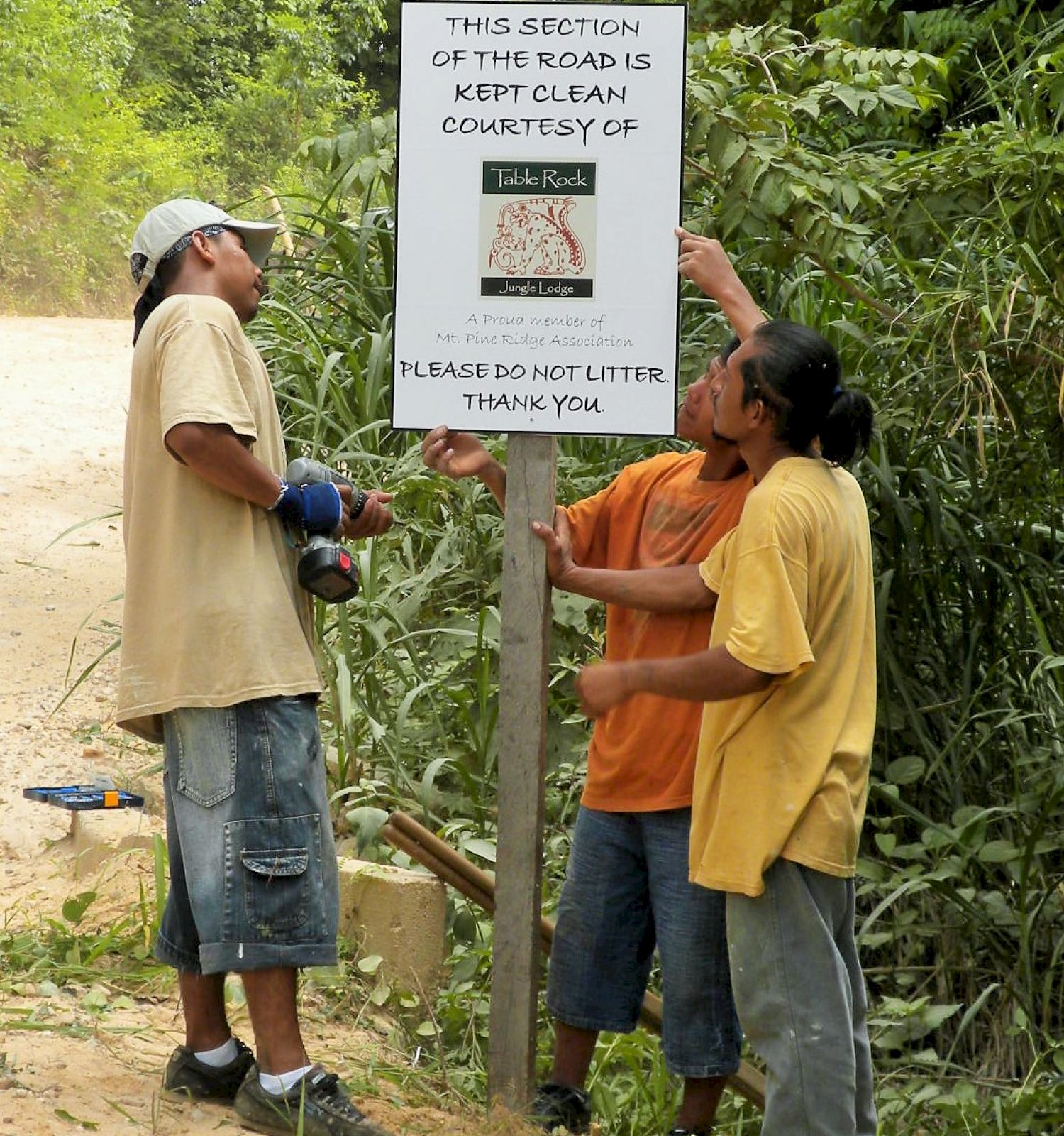 Three people are installing a sign that reads, 