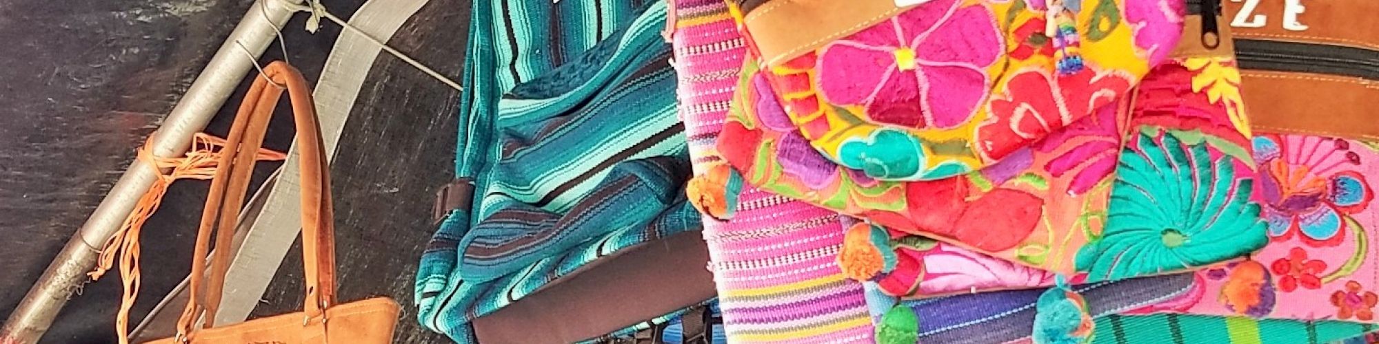 The image shows colorful, embroidered bags hanging on display, likely at a market.