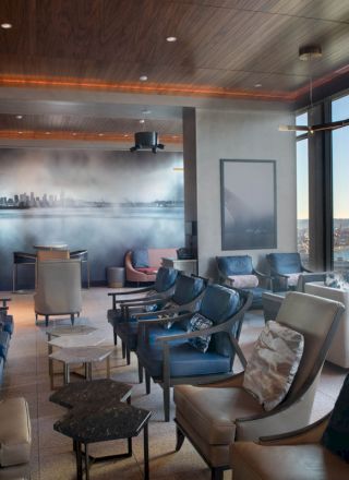 A modern lounge area with comfortable seating, large windows offering a scenic view, and a mural on the back wall.